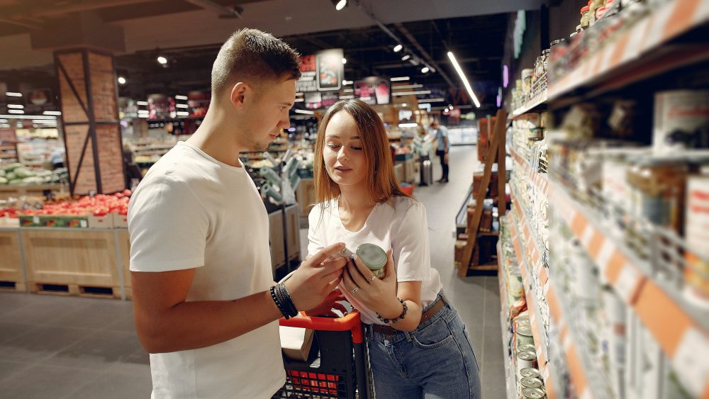A ypung couple choosing food items in a store by a shelf